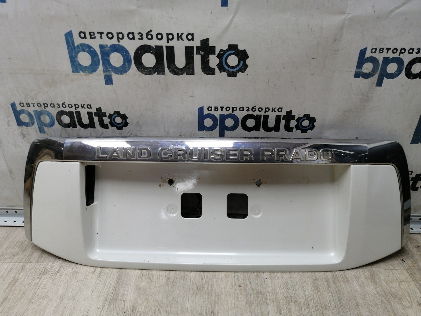 Пример детали Накладка крышки багажника, без кнопок (76811-60190); Toyota Land Cruiser Prado 150 (2010 — 2013) /AA045274/ БУ; Оригинал; Р0, Хорошее; (070) Белый перламутр 3х. сл.