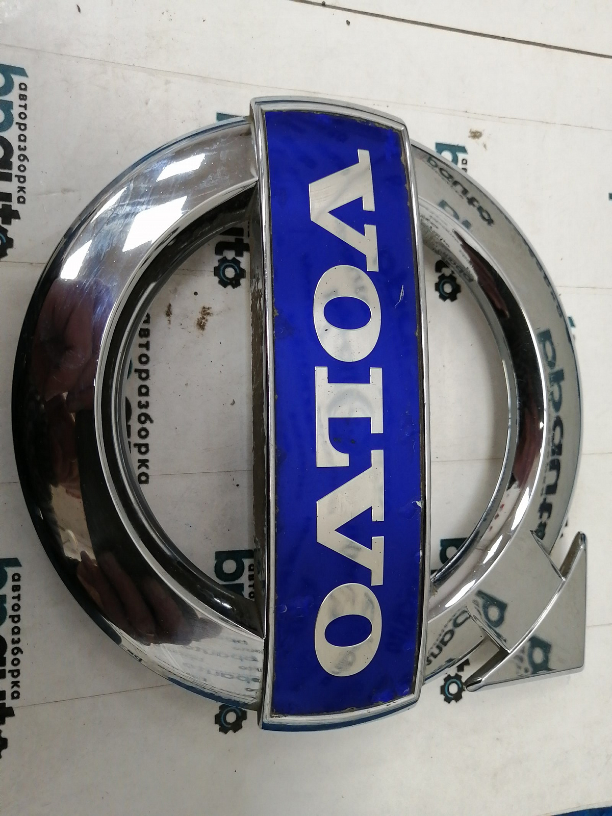 Пример детали Эмблема решетки радиатора (30796425); Volvo XC60 I (2008-2013), I рест. (2013-2017) /AA038087/ БУ; Оригинал; Р1, Мелкий дефект; 