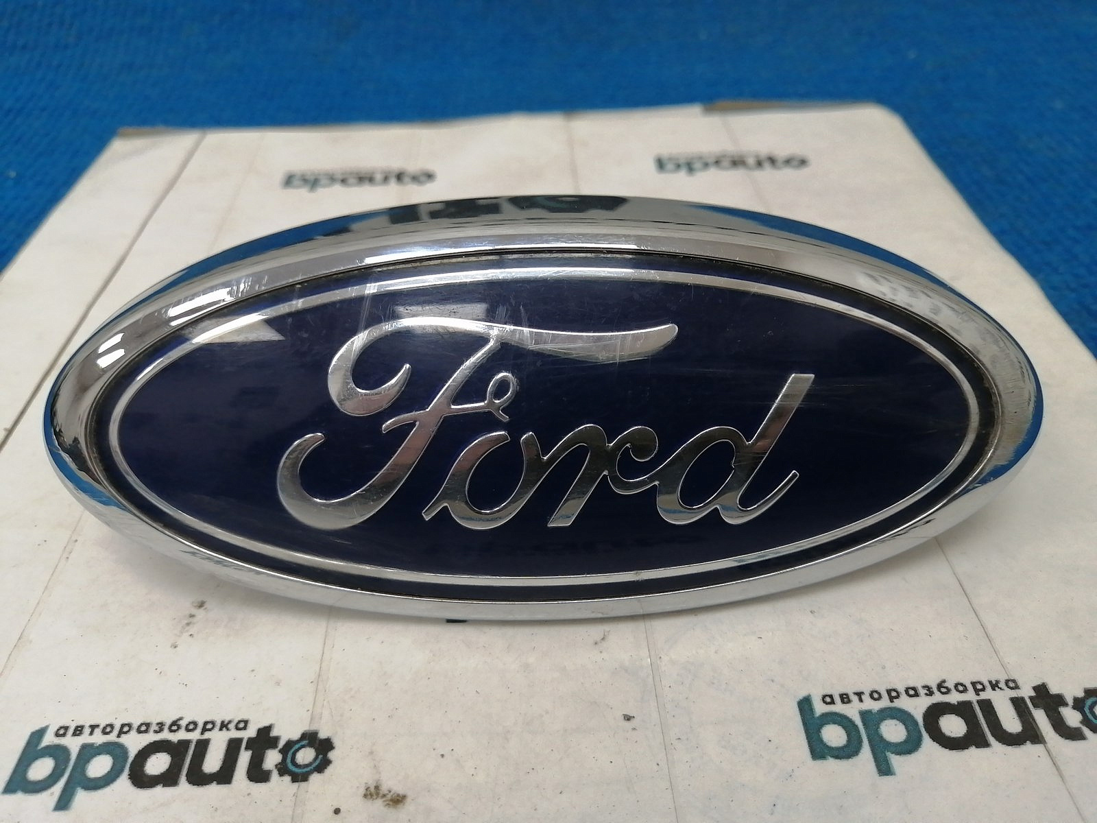 Фотография детали AA038057; Эмблема на решетку радиатора (4M518216AA) для Ford Focus/БУ; Оригинал; Р0, Хорошее; . Фото номер 1